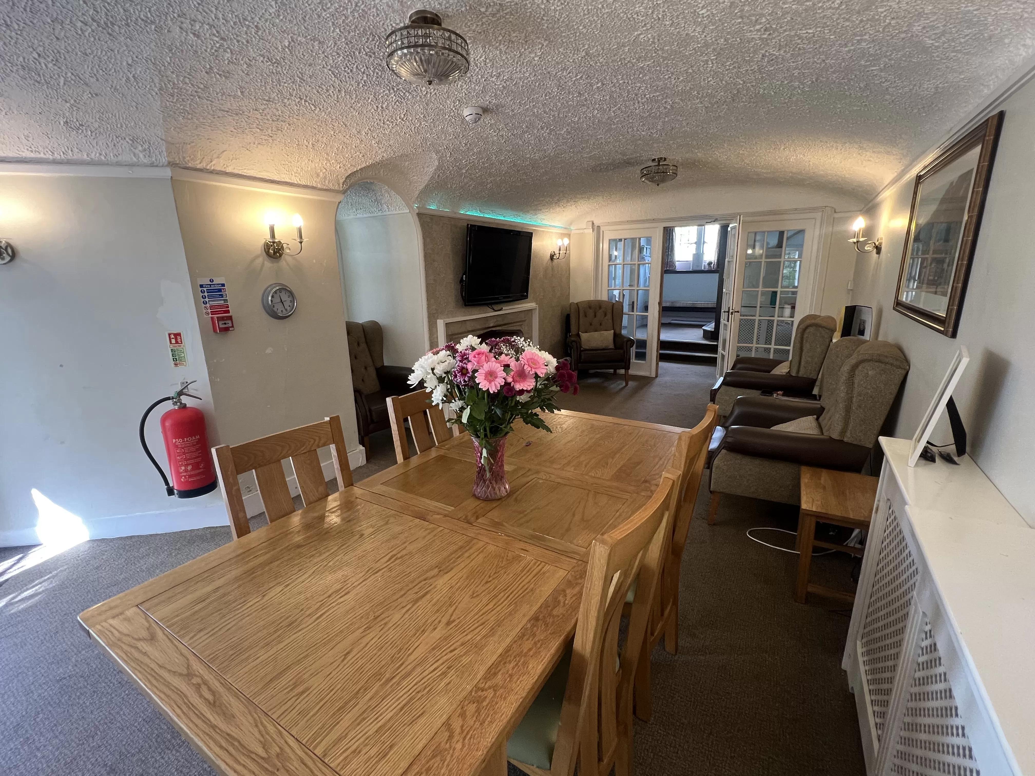 A dining room featuring a wooden table surrounded by four chairs, with soft lighting and a neutral color scheme.