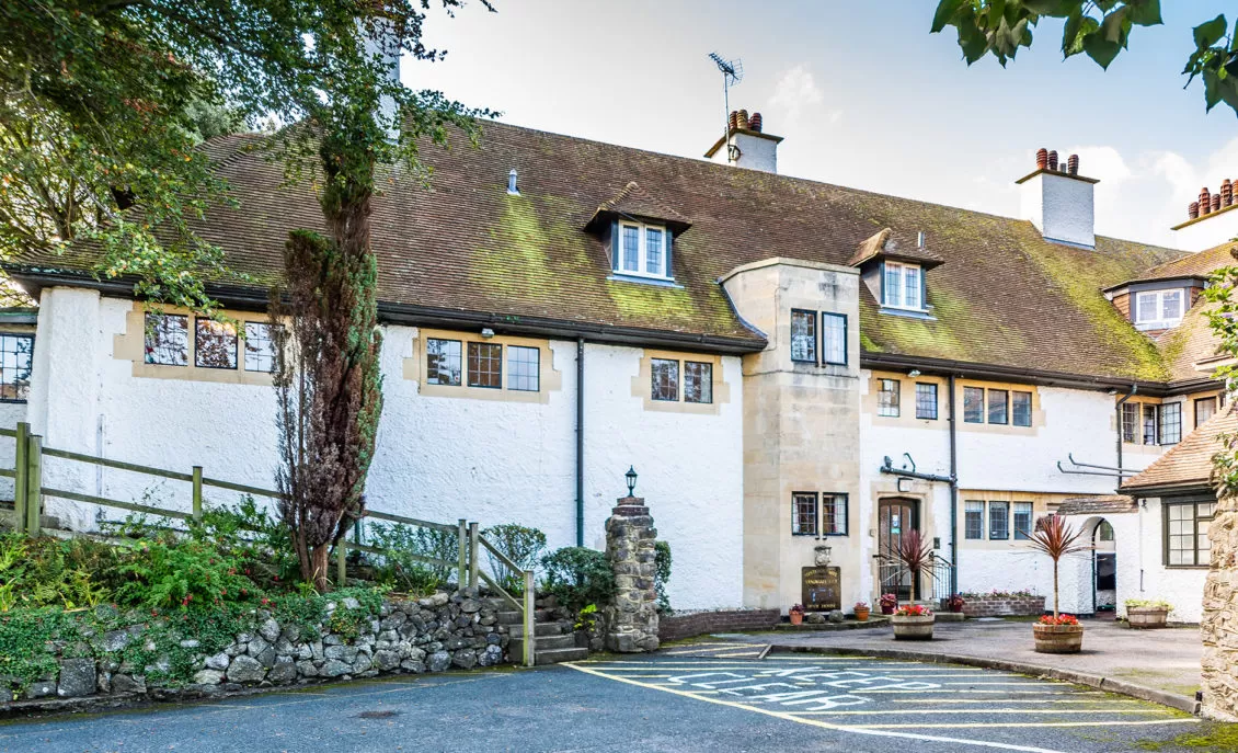 A large white building with a modern architectural design, featuring multiple windows and a clear blue sky in the background.